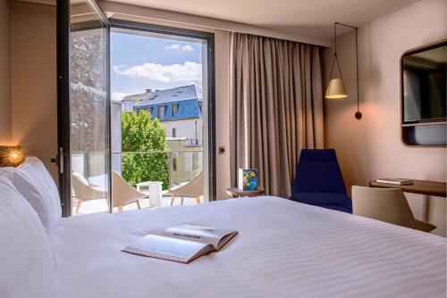 a hotel room with a bed with a book and a window at Radisson Blu Hotel, Rouen Centre in Rouen
