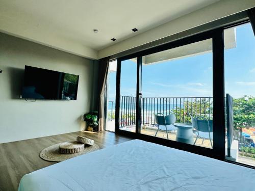 a bedroom with a bed and a balcony with a television at 厝True Hub旅店 in Nanwan