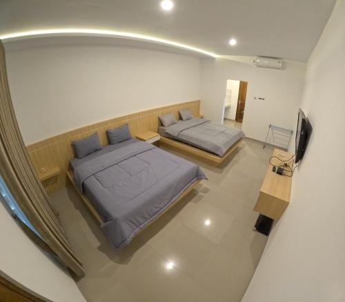 1 dormitorio con 2 camas y TV. en Joglo Riverside, en Kejayan