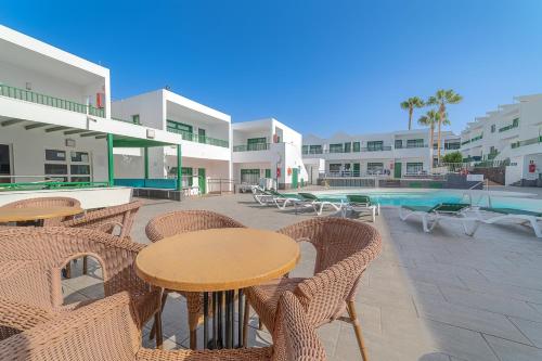 a patio with tables and chairs next to a pool at Apartamentos Elena in Puerto del Carmen