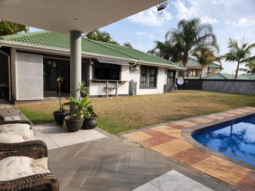 un patio trasero con piscina y una casa en Umhlanga Guesthouse flat, en Durban