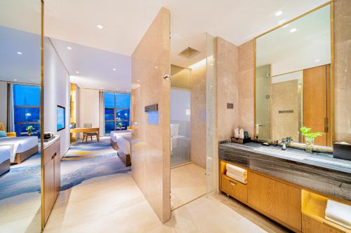 a bathroom with a large mirror and a bedroom at Wyndham Shiyan Downtown in Shiyan