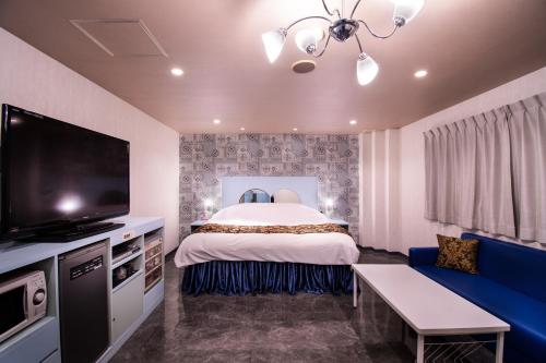 ein Hotelzimmer mit einem Bett und einem Flachbild-TV in der Unterkunft Koriyama Flower Style in Tenri