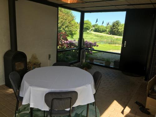 einen weißen Tisch und Stühle in einem Zimmer mit einem großen Fenster in der Unterkunft Harvey`s Bed & Breakfast in Hjørring