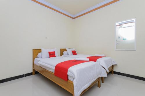una camera da letto con un letto con cuscini bianchi e rossi di RedDoorz Syariah near Alun Alun Pasuruan a Pasuruan