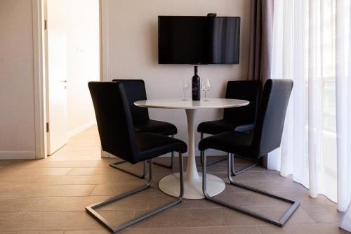 a white table with black chairs and a tv on a wall at The SPOT apartments - Orbi Beach Tower in Batumi