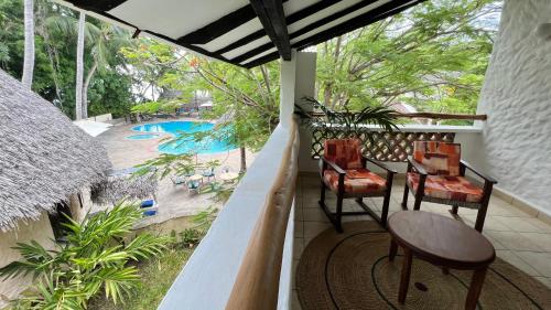 a porch with chairs and a table and a pool at Pinewood Beach Resort and Spa in Diani Beach