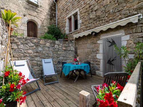 een patio met een tafel en stoelen op een houten terras bij Holiday Home Le Rouge Borne - LVS110 by Interhome in Sainte-Marguerite-Lafigère