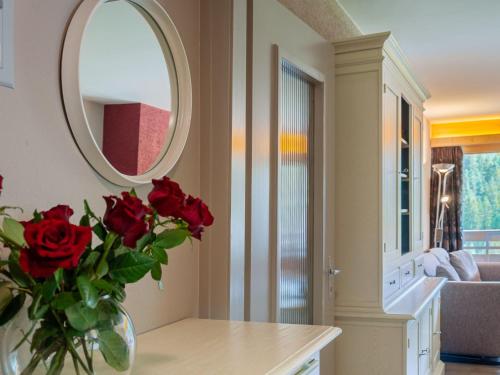 a vase of red roses on a table with a mirror at Apartment Rosablanche C61 by Interhome in Siviez