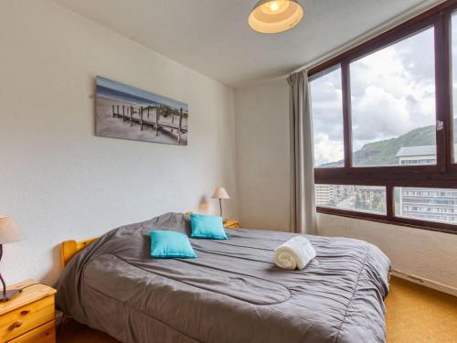 a bedroom with a bed with blue pillows and a window at Apartment Grande Masse-2 by Interhome in Les Menuires