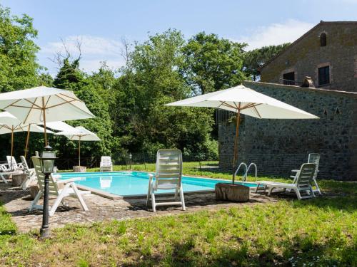 a swimming pool with two chairs and umbrellas at Apartment La Capraccia-5 by Interhome in Bagnoregio