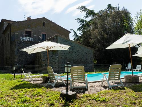 a group of chairs and umbrellas next to a pool at Apartment La Capraccia-9 by Interhome in Bagnoregio