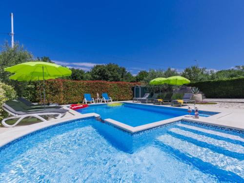 a swimming pool with chairs and umbrellas in a yard at Holiday Home Villa Anamaria by Interhome in Plovanija