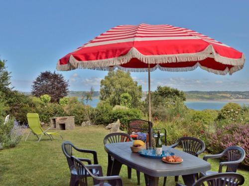 - une table avec un parasol et des chaises rouges et blancs dans l'établissement Holiday Home Ker Norge by Interhome, à Plestin-les-Grèves