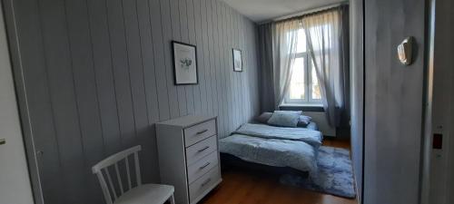 a small bedroom with a bed and a dresser and a window at Kamienica 1910 roku in Morąg