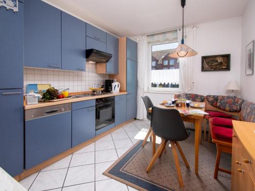 ノルトダイヒにあるApartment Baltrum-Badestrasse by Interhomeのキッチン(青いキャビネット、テーブル、椅子付)