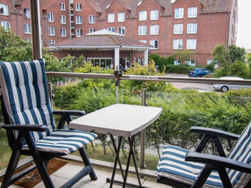 2 Stühle und ein Tisch auf einem Balkon mit einem Gebäude in der Unterkunft Apartment Baltrum-Badestrasse by Interhome in Norddeich
