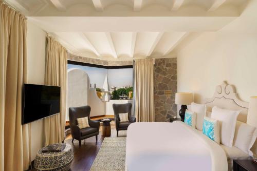 a hotel room with a bed and chairs and a television at Banyan Tree Puebla in Puebla