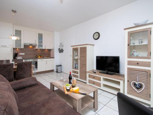 ein Wohnzimmer mit einem Sofa, einem TV und einem Tisch in der Unterkunft Apartment Seestern by Interhome in Norddeich