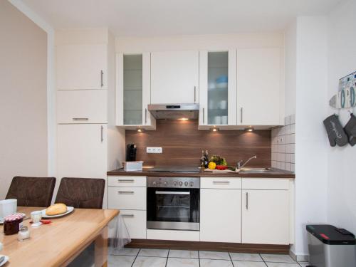 eine Küche mit weißen Schränken und einem Holztisch in der Unterkunft Apartment Seestern by Interhome in Norddeich