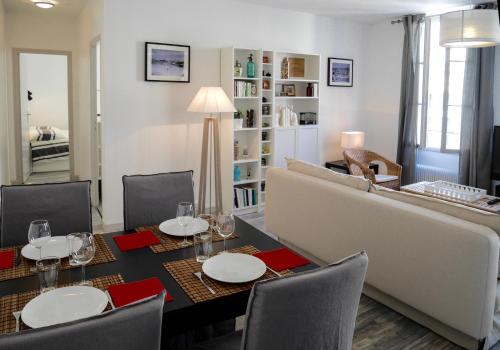 ein Esszimmer mit einem Tisch und einem Sofa in der Unterkunft Les Appartements de Cyrano in Bergerac