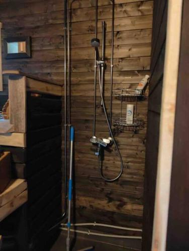eine Dusche im Bad mit einer Holzwand in der Unterkunft Mökki Mannervaarassa, Joensuussa in Mannervaara
