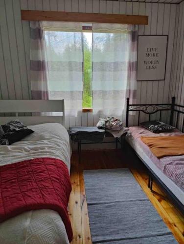 1 Schlafzimmer mit 2 Einzelbetten und einem Fenster in der Unterkunft Mökki Mannervaarassa, Joensuussa in Mannervaara