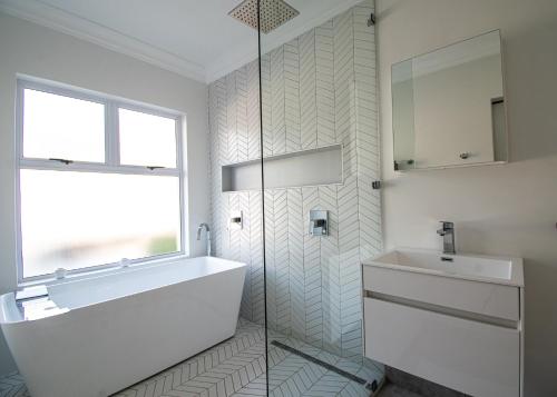 a bathroom with a tub and a sink and a window at 4 Sea Breeze Umhlanga Rocks in Umhlanga