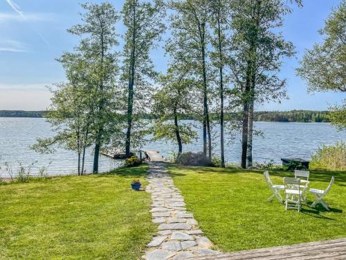 a stone path leading to a lake with chairs at Holiday Home Villa aava by Interhome in Siksalo