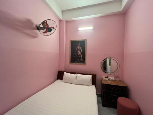 a small pink bedroom with a bed and a mirror at Nhà nghỉ 2552, đường D4 , KDC Võ Thị Sáu , phường Thống Nhất , thành phố Biên Hòa in Bien Hoa