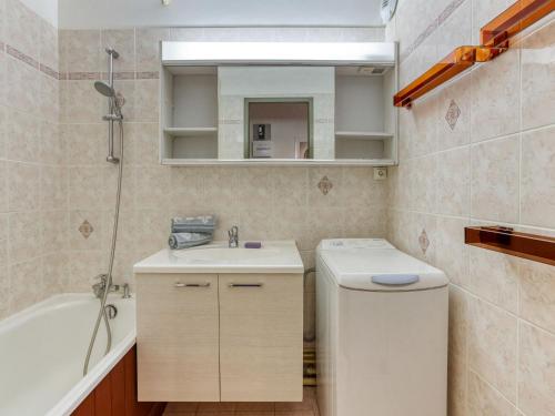 uma casa de banho com um lavatório, uma banheira e um espelho. em Apartment Chanteneige La Croisette-1 by Interhome em Les Menuires