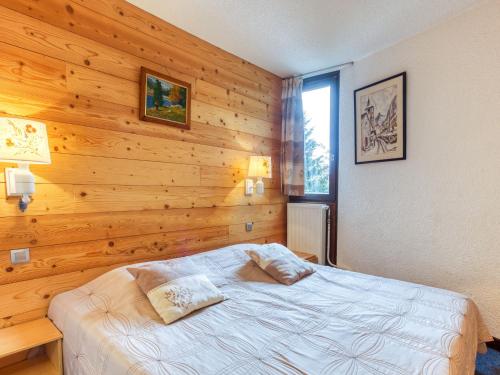 - une chambre avec un lit et un mur en bois dans l'établissement Apartment Chanteneige 505 by Interhome, aux Menuires