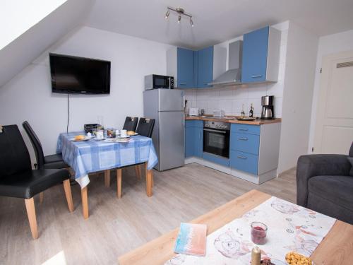 a living room with a table and a kitchen with blue cabinets at Apartment Fischerstube by Interhome in Norddeich