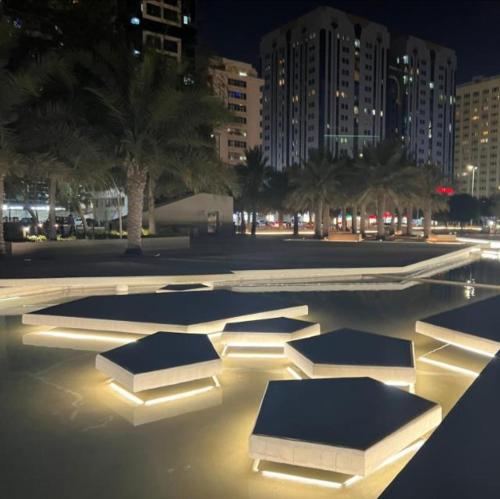 a swimming pool with lights in a city at night at Abu Dhabi Centre - Elegant Spot in Abu Dhabi