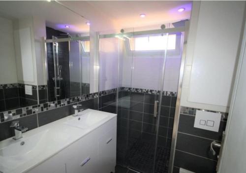 y baño con lavabo, ducha y espejo. en Belle villa climatisée de 105m² en bord de mer., en Frontignan