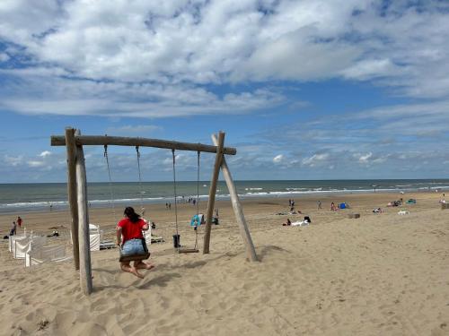 een vrouw speelt op een schommel op het strand bij Holiday Home de Witte Raaf-2 by Interhome in Noordwijk