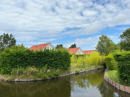 a river with bushes and houses in the background at Holiday Home Plevier Comfort-2 by Interhome in Noordwijk