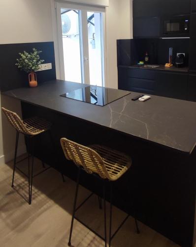 eine Küche mit einer schwarzen Theke und 2 Stühlen in der Unterkunft Logroño Centric in Logroño