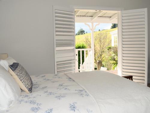 a white bedroom with a bed and a balcony at Maleny Homestead & Cottage in Maleny