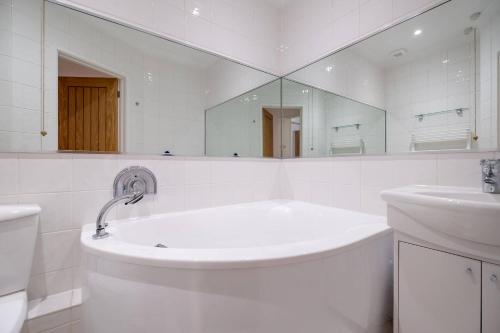 Un baño blanco con bañera y lavabo. en High Tide, en Milford on Sea