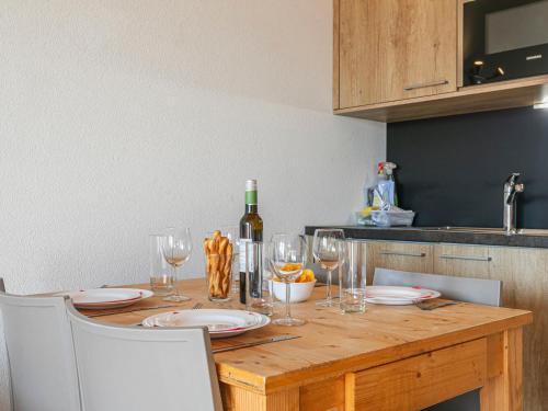 uma mesa de madeira com copos e uma garrafa de vinho em Apartment T-Resort La Tzoumaz 2p4 by Interhome em La Tzoumaz