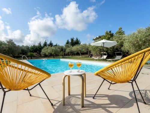 dos copas de vino sentadas en una mesa junto a una piscina en Holiday Home Casale Colomba by Interhome, en Case dʼAmico