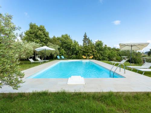 a swimming pool in a yard with chairs and umbrellas at Holiday Home Casale Colomba by Interhome in Case dʼAmico
