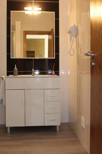 a bathroom with a sink and a mirror and a shower at Casa Carvalho Laranjo in Nazaré