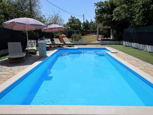 una piscina azul con 2 sillas y una sombrilla en Holiday Home Labin by Interhome, en Labin