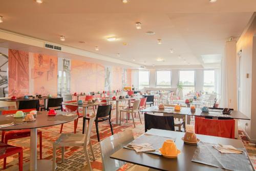 - un restaurant avec des tables et des chaises dans une salle dans l'établissement Holiday Inn Mulhouse, an IHG Hotel, à Mulhouse