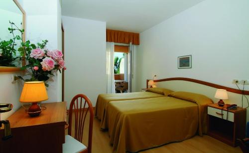 una camera con letto e tavolo con lampada di Hotel Garni Losanna a Bibione