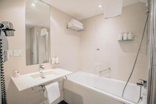 a white bathroom with a sink and a shower at Holiday Inn Mulhouse by IHG in Mulhouse