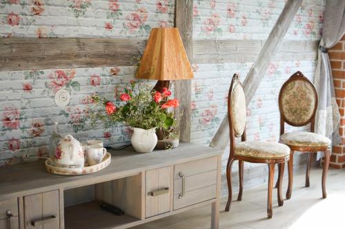 a room with a table with a lamp and two chairs at Osada Między Drzewami in Braniewo