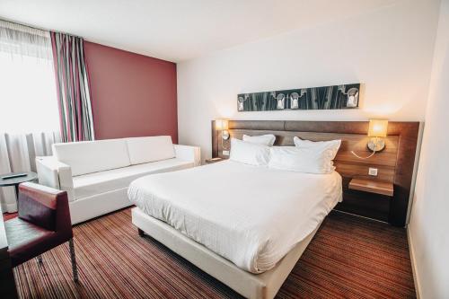 a hotel room with a bed and a couch at Holiday Inn Mulhouse by IHG in Mulhouse